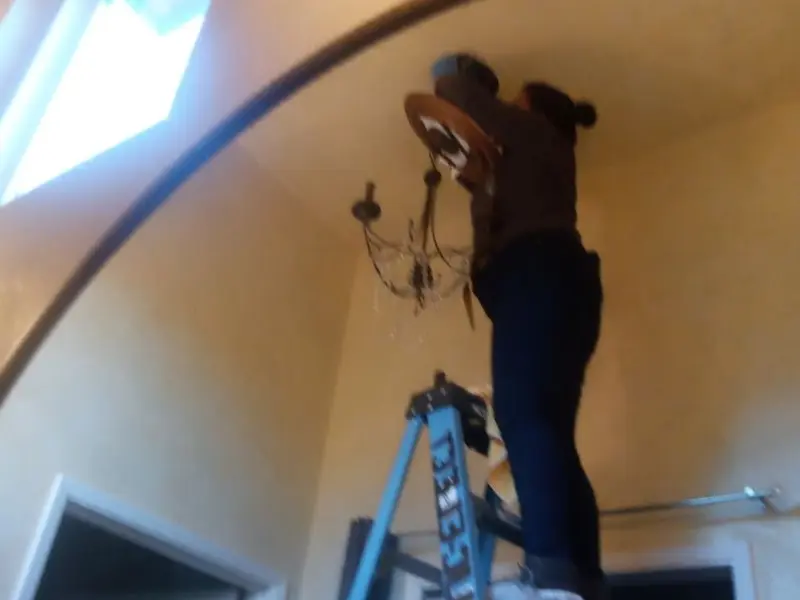 Electrician installing a chandelier in a Litchfield residence